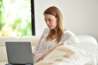 © goodluz - Woman relaxing in sofa and websurfing with laptop