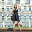 Young beautiful woman in black dress posing outdoors in sunny we