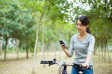 Wall Mural - Woman checking the GPS on mobile phone when cycling