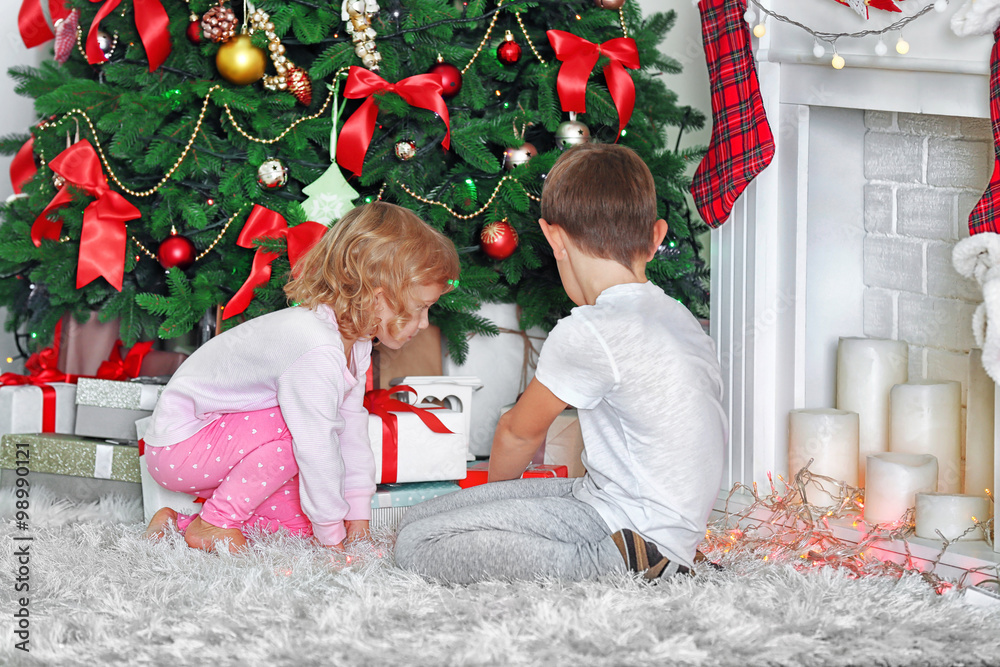 Funny kids with gift boxes and Christmas tree on background