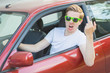 Junger Mann mit Sonnenbrille sitzt im Auto und zeigt Mittelfinge