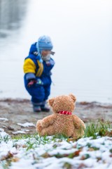 Little boy and teddy bear on lake shore