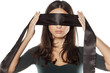 serious woman adjusts blindfold over her eyes