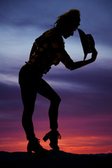 Wall Mural - silhouette of woman with cowboy hat lean over in the sunset