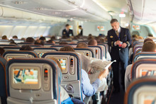 Steward And Passengers On Commercial Airplane.