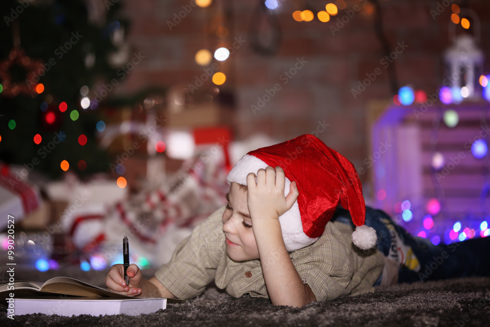 Little boy writing in notebook on a Christmas background