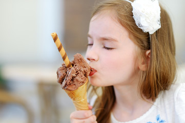 Wall Mural - Adorable little girl eating tasty fresh ice cream outdoors