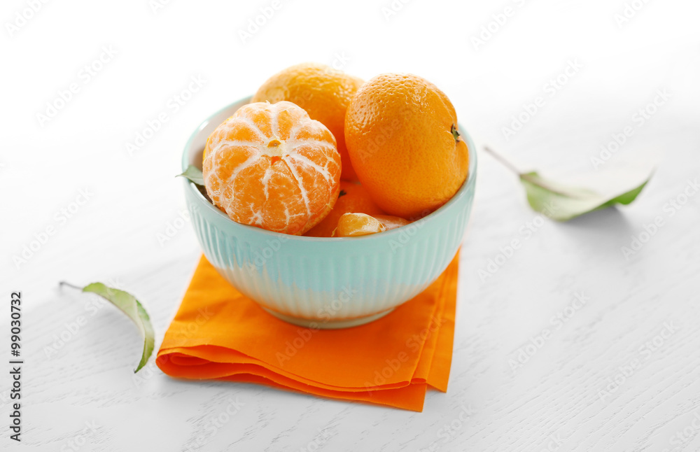 Tangerines in bowl on white wooden table, close up