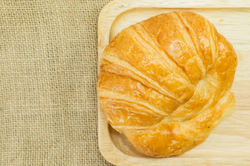 Wall Mural - butter croissant on wooden plate on gunny sack texture, top view with copy space