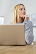 © contrastwerkstatt - frau sitzt zuhause am laptop und schaut in gedanken zur seite