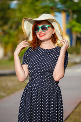 Wall Mural - Young woman in polka-dot dress and straw hat 