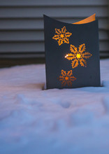Lit Luminary With Glowing Snowflakes Light Up Snow Covered  Front Steps Of A Home
