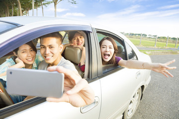 Wall Mural - young  people enjoying road trip in the car and making selfie