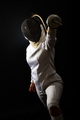 Portrait of woman wearing white fencing costume practicing with the sword. Isolated on black background.