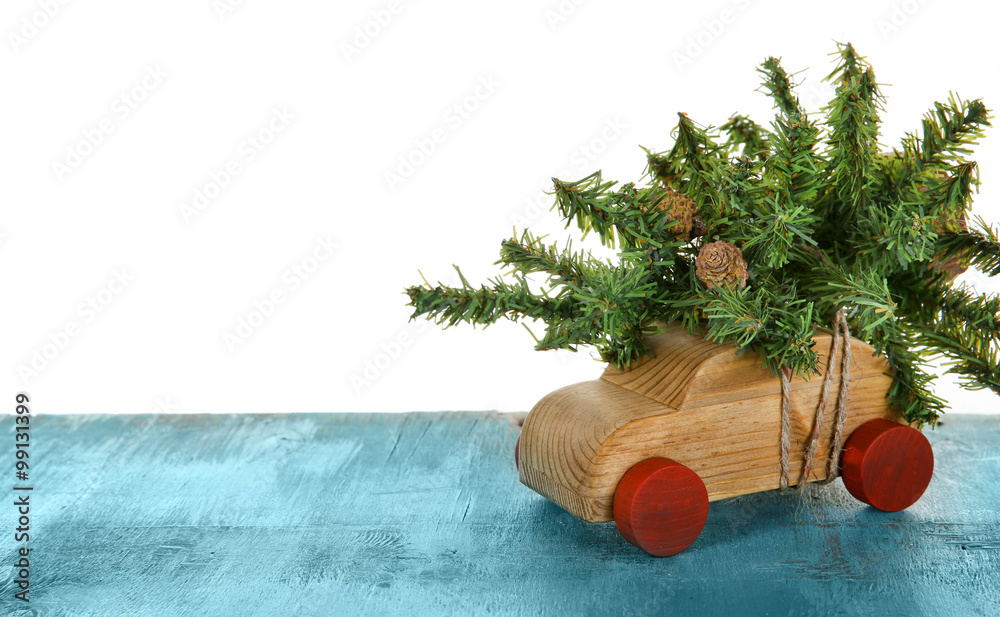 Wooden toy car with Christmas tree on a table over white background