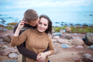 Wall Mural - Young couple hugging on a rocky seashore