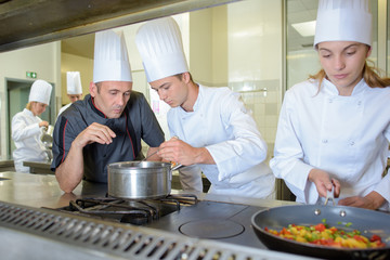 Chef checking work of trainee cooks