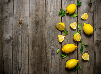 Lemons sliced and whole with leaves .