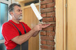 © sima - Worker installing wooden door, using polyurethane foam