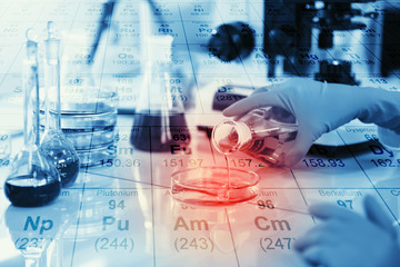 Science, chemistry, technology, biology and people concept - young female scientist mixing reagents from glass flasks and making test or research in clinical laboratory with chemical table background.