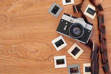 Vintage camera, slides and negatives on wooden background