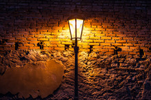 Vintage Street Lamp Against A Brick Wall At Night