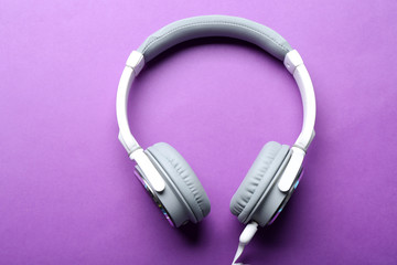 White and grey headphones on purple background