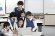 © Blue Jean Images - Students and teacher gathered around a computer in the classroom