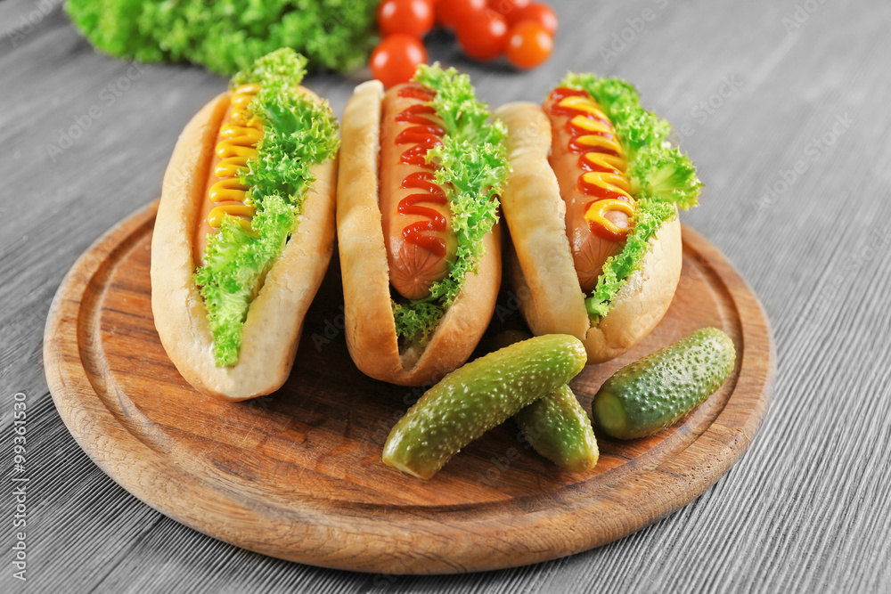 Tasty hot-dogs with vegetables on wooden table