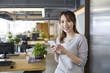 © Blue Jean Images - Young woman using smart phone in office
