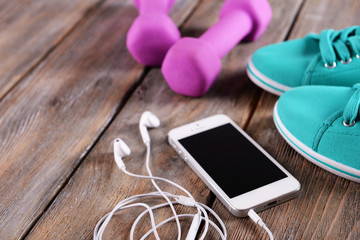 Poster - White cellphone with headphones and pink dumb bells and gumshoes on wooden background