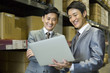 © Blue Jean Images - Business partners with laptop in logistic warehouse