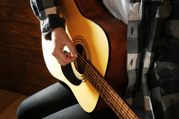 Wall Mural - Guitarist plays guitar on wooden background, close up