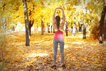 Young beautiful woman doing sport exercises in autumn park