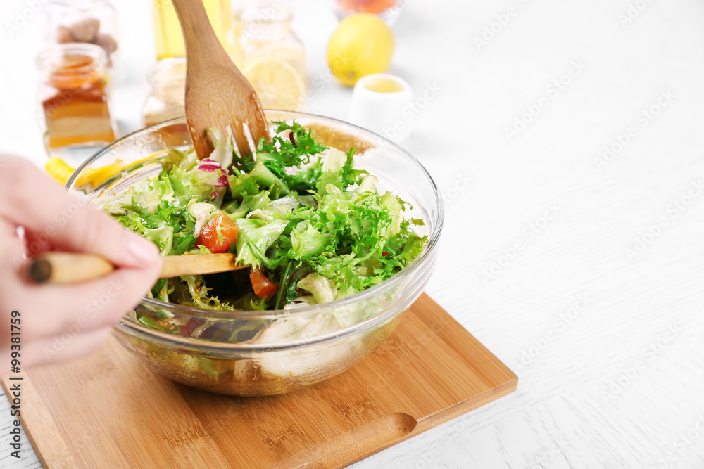 Young man preparing healthy salad, close-up