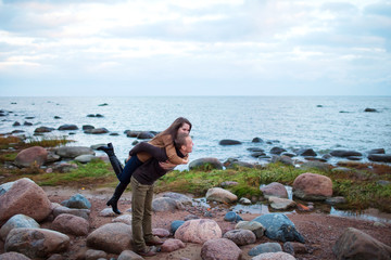 Wall Mural - young couple sitting on a rock on the beach