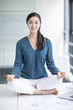 © Blue Jean Images - Young businesswoman doing yoga on office desk