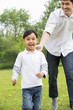 © Blue Jean Images - Happy father and son running on the grass
