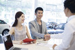 © Blue Jean Images - Young couple buying car in showroom
