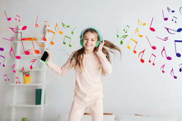 Wall Mural - girl jumping on bed with smartphone and headphones