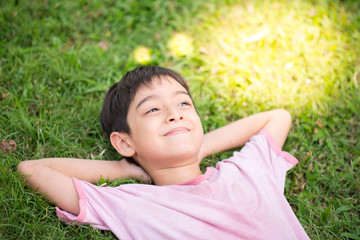 Little boy laying down on the grass dreaming light