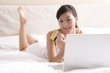 © Blue Jean Images - Asian woman on bed with a laptop