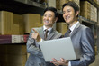 © Blue Jean Images - Business partners with laptop in logistic warehouse