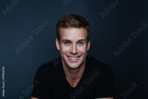 Plakát Portrait photo of young happy man with a blinding smile in v nec