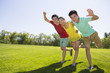 © Blue Jean Images - Three cheerful young adults standing arm in arm on grass