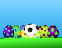 Row Of Brightly Painted Easter Eggs Siting In The Grass.  The Center Egg Is Cracked Open With A Soccer Ball Inside.