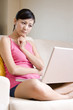 © Blue Jean Images - Asian woman on a sofa with a laptop