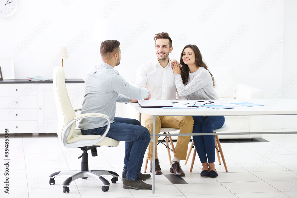 Happy family with estate agent,  in bright office