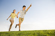 © Blue Jean Images - Cheerful young couple holding hands running on grass