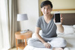 © Blue Jean Images - Young man showing smart phone on bed